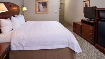 Habitación de hotel con una cama grande, televisión, cómoda y un cuadro en la pared.