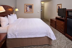 Habitación de hotel con una cama grande, televisión, cómoda y un cuadro en la pared.