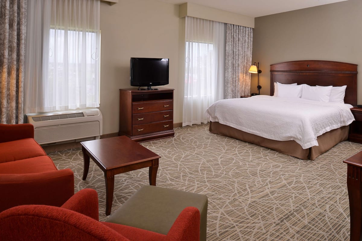 A hotel room with a bed, a TV, a desk, and a sofa.