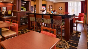 A hotel lobby with a bar area, seating arrangements, and a clock on the wall. - Hampton Inn by Hilton Litchfield (Litchfield)