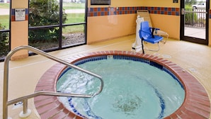 A hot tub with a metal ladder, a blue chair, and a tiled wall with a notice sign. - Hampton Inn by Hilton Litchfield (Litchfield)