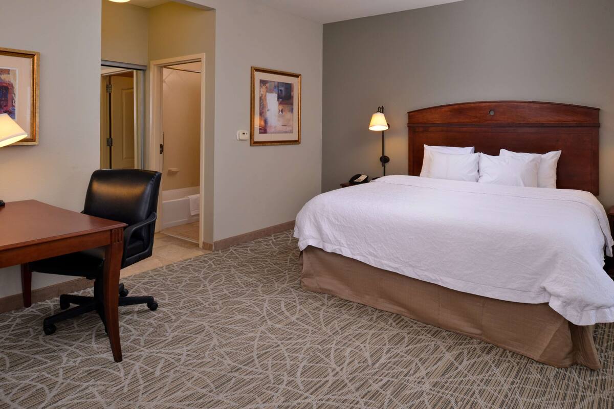 A hotel room with a bed, a desk, and a chair.