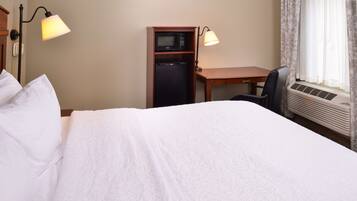 A hotel room with a bed, a desk, a microwave, and a chair.