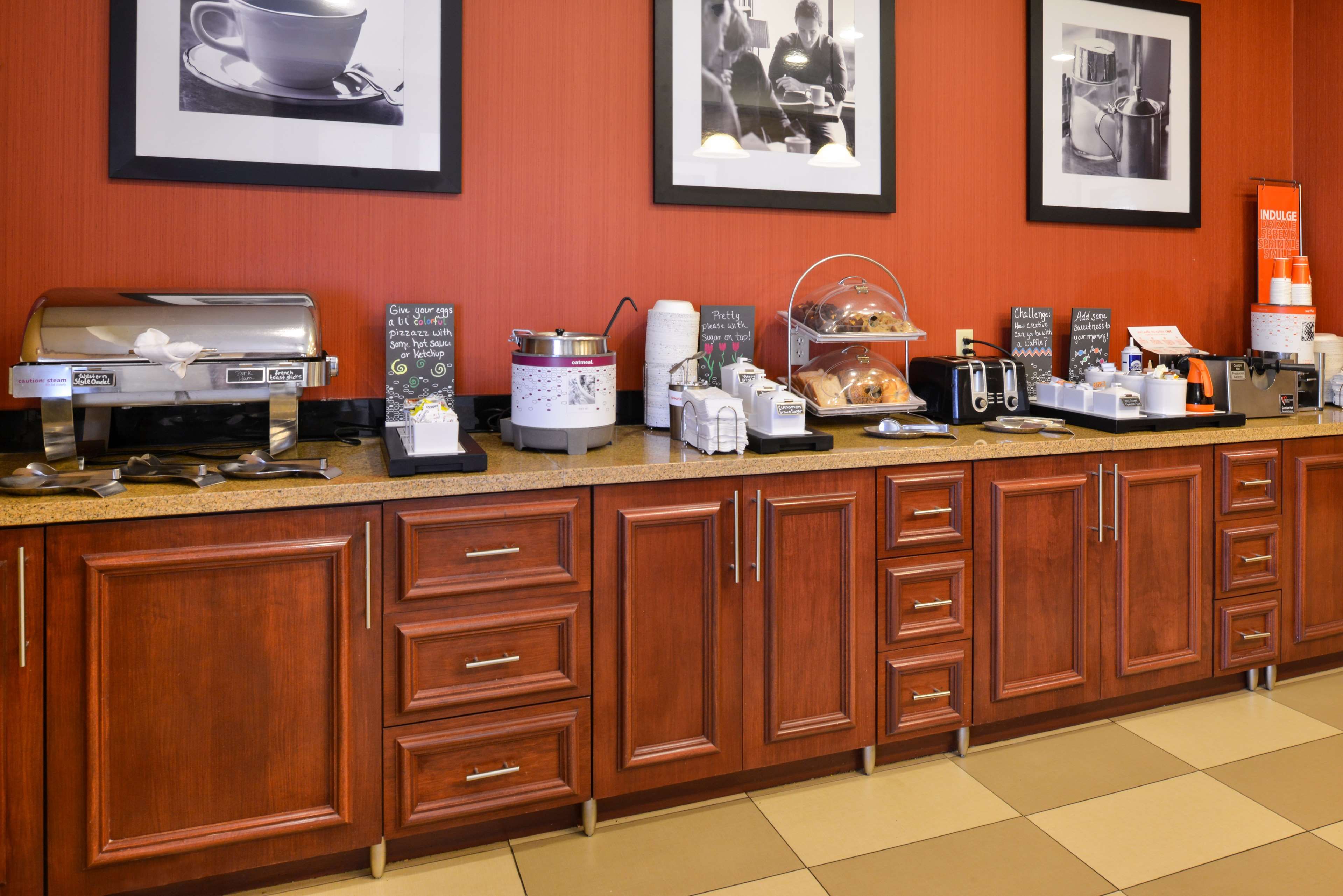 Una barra de desayuno con una máquina de café, una plancha para gofres y diversas opciones para el desayuno.