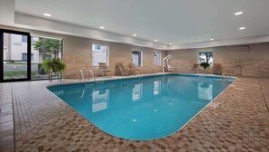 An indoor swimming pool with clear glass walls, a tiled floor, and a few chairs and plants around the pool area. - Hampton Inn & Suites Dayton - Vandalia (Dayton)