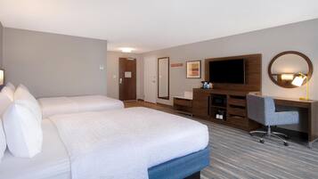 Quarto de hotel com uma cama grande, uma escrivaninha com cadeira, televisão e um espelho.