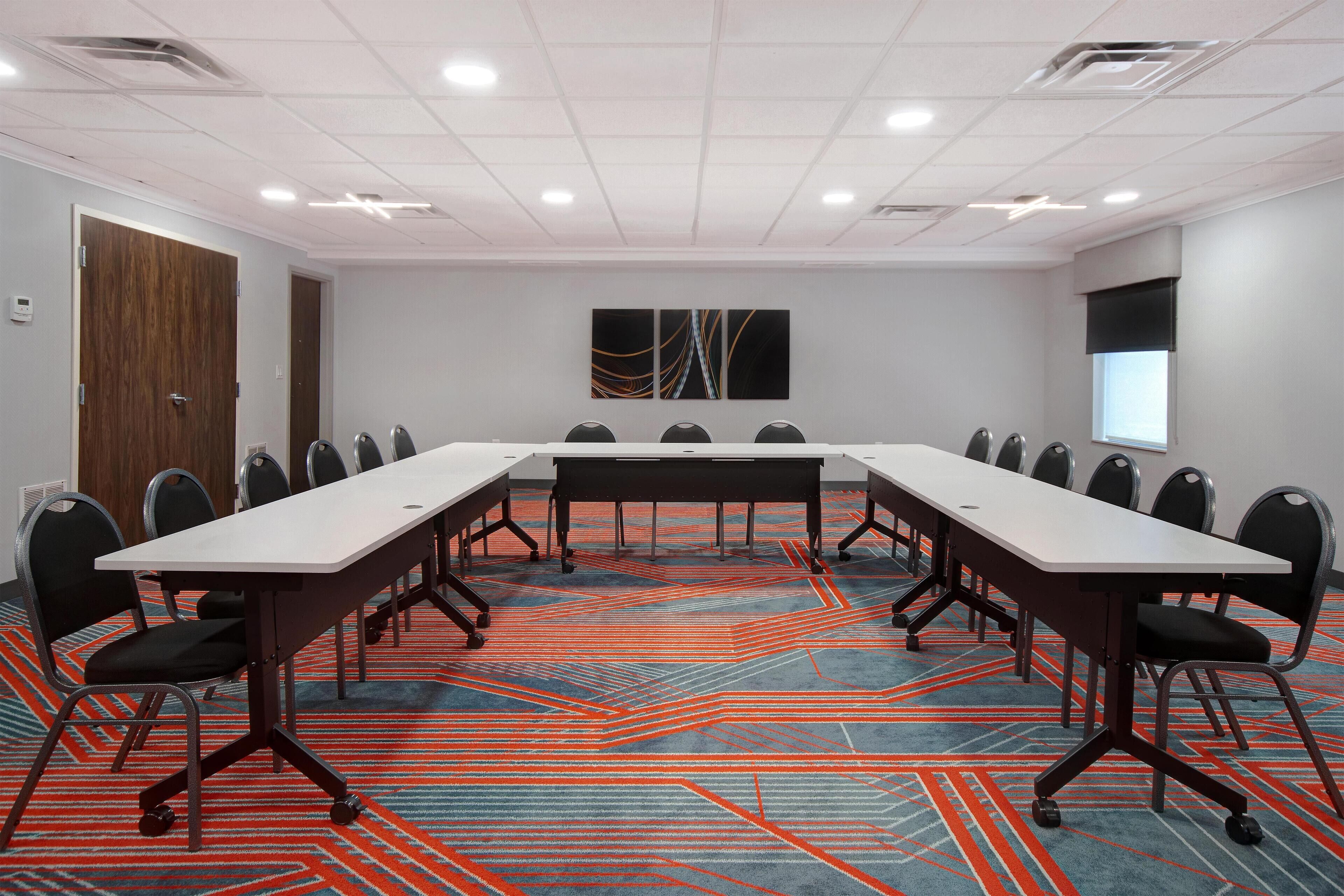 Un salón de conferencias con una larga mesa, sillas y suelo alfombrado.