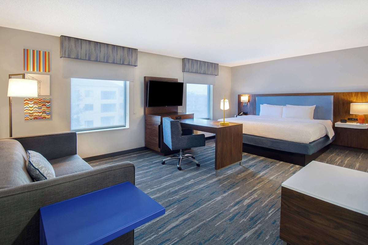 Habitación de hotel con cama, escritorio, sillón, sofá y televisión.