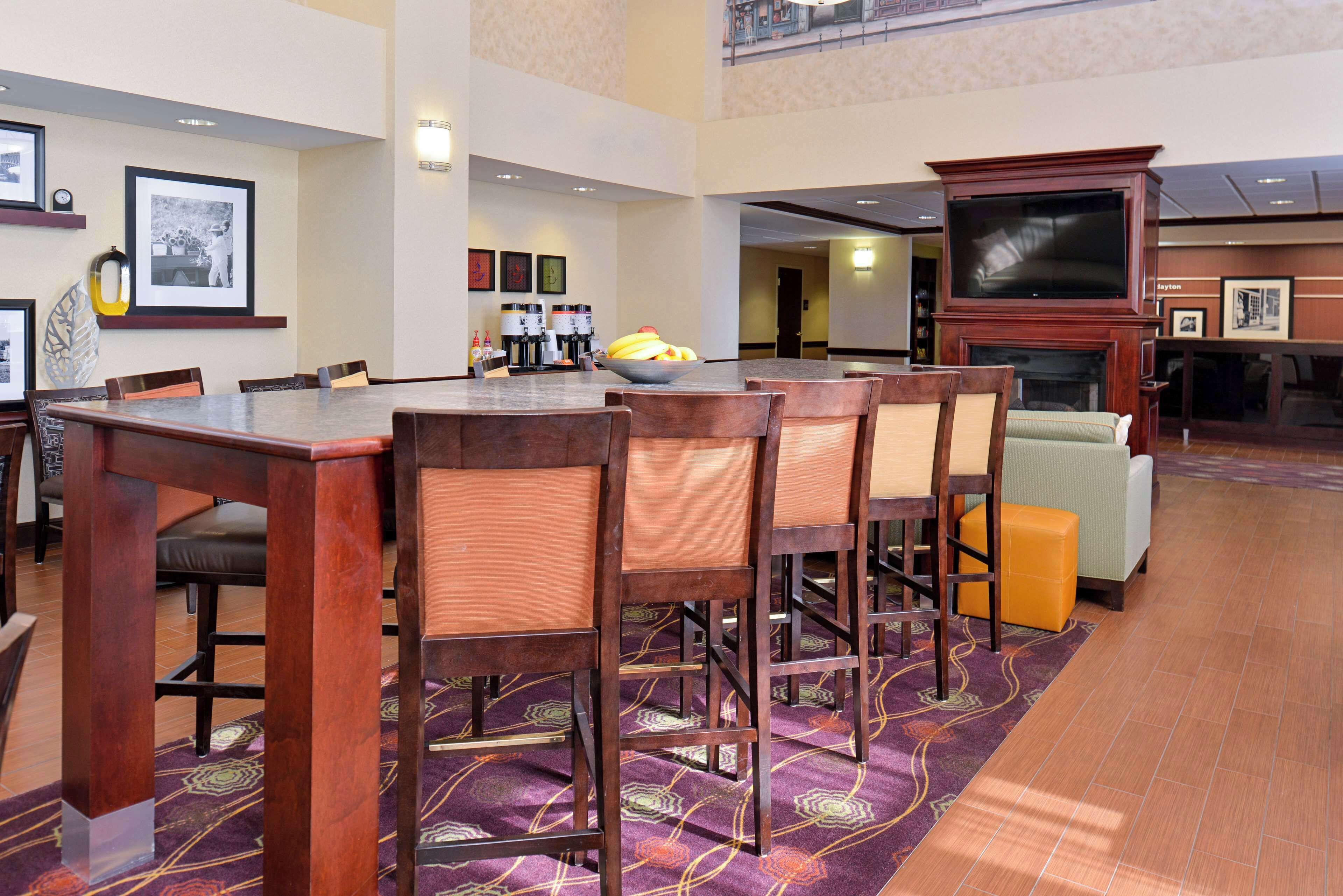 A hotel lobby with a dining area, a fireplace, and a television.