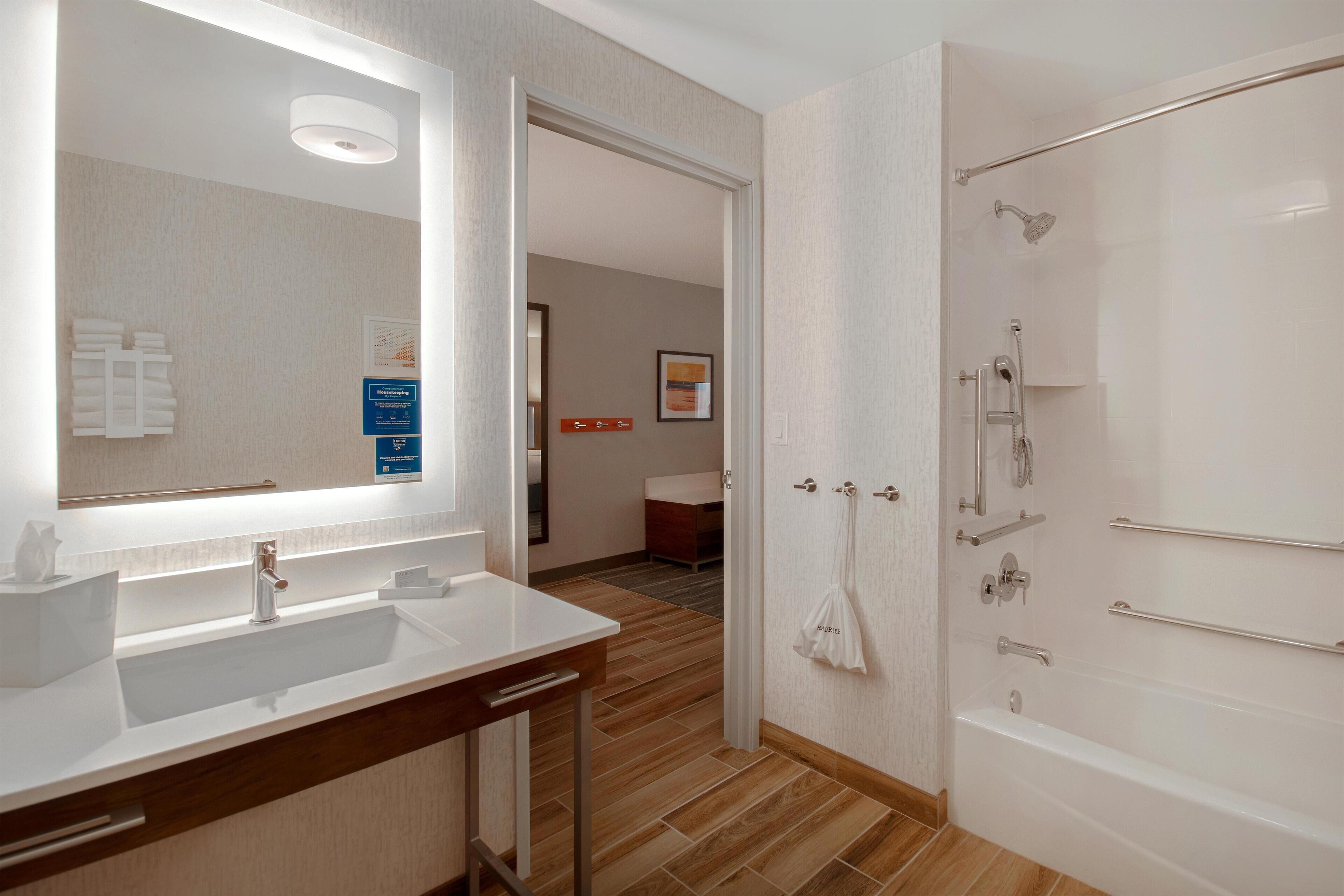 A modern bathroom with a large mirror, a sink, and a shower area.