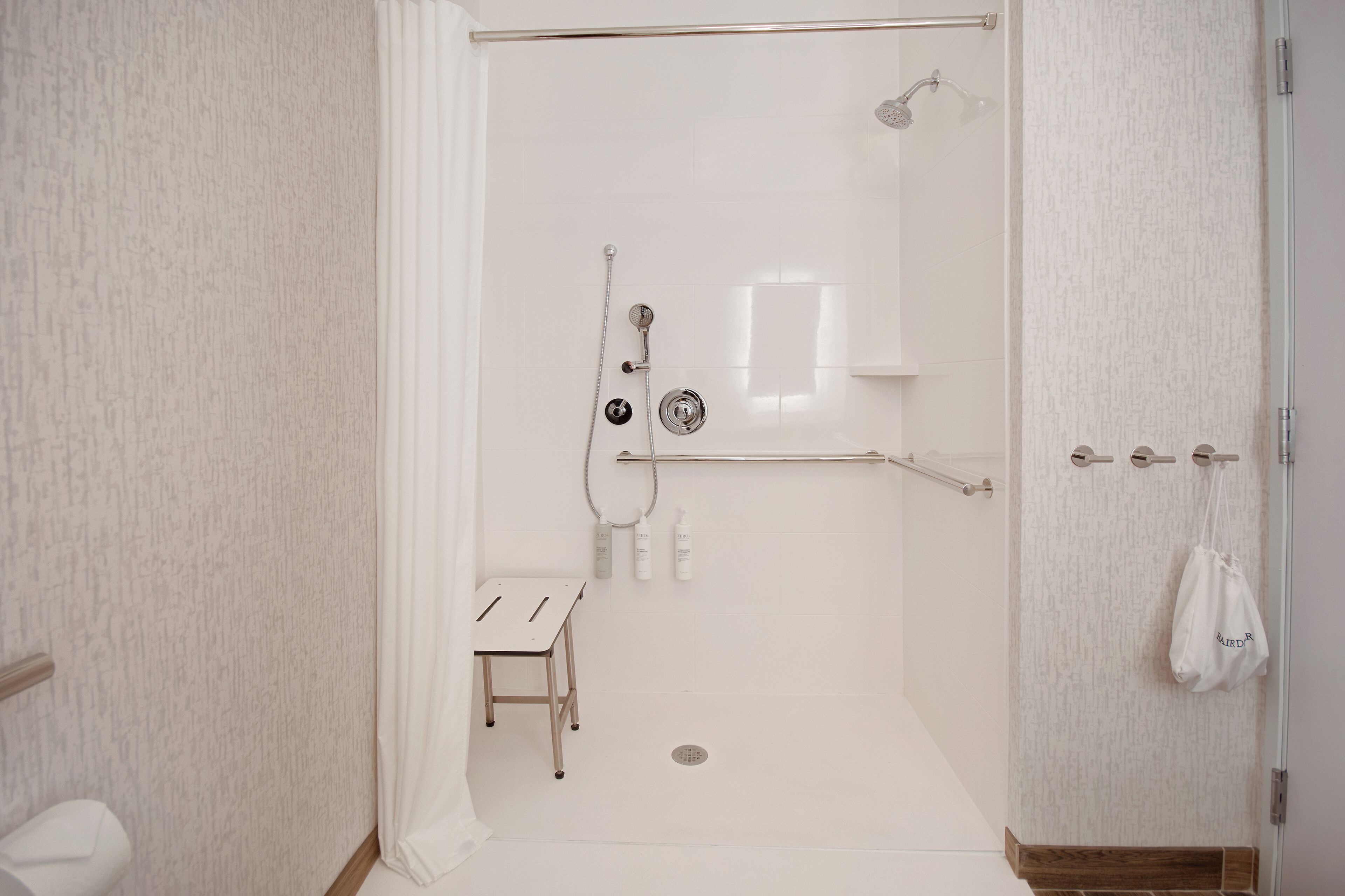 A modern bathroom with a walk-in shower, a small table, and a towel rack.
