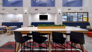 A modern dining area with a large table, black chairs, and a central plant display. - Hampton Inn & Suites Dayton - Vandalia (Dayton)