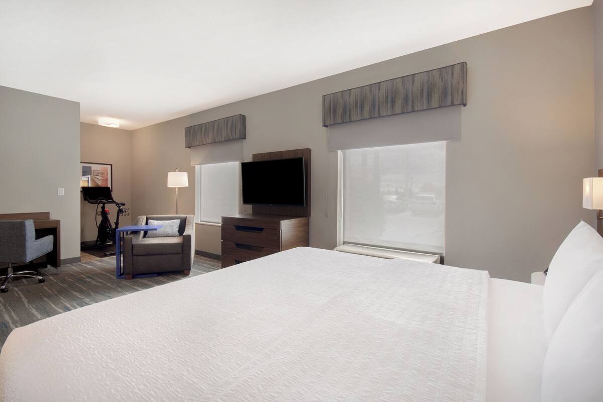 Habitación de hotel con una cama grande, un escritorio, una silla, un televisor y una ventana.