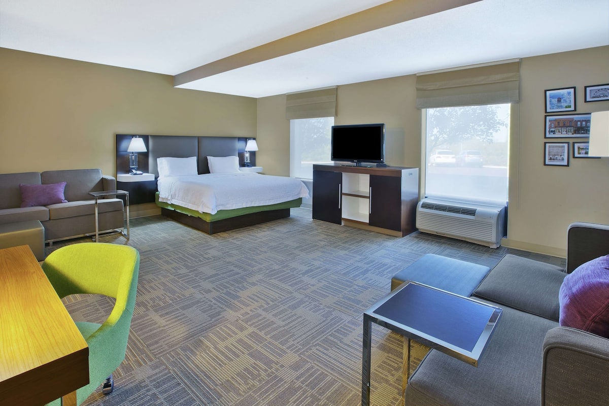 A hotel room with a bed, a desk, a television, a sofa, and a chair.