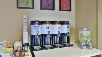 A coffee station with multiple dispensers, a glass jar with lemons, and various coffee pods and cups.