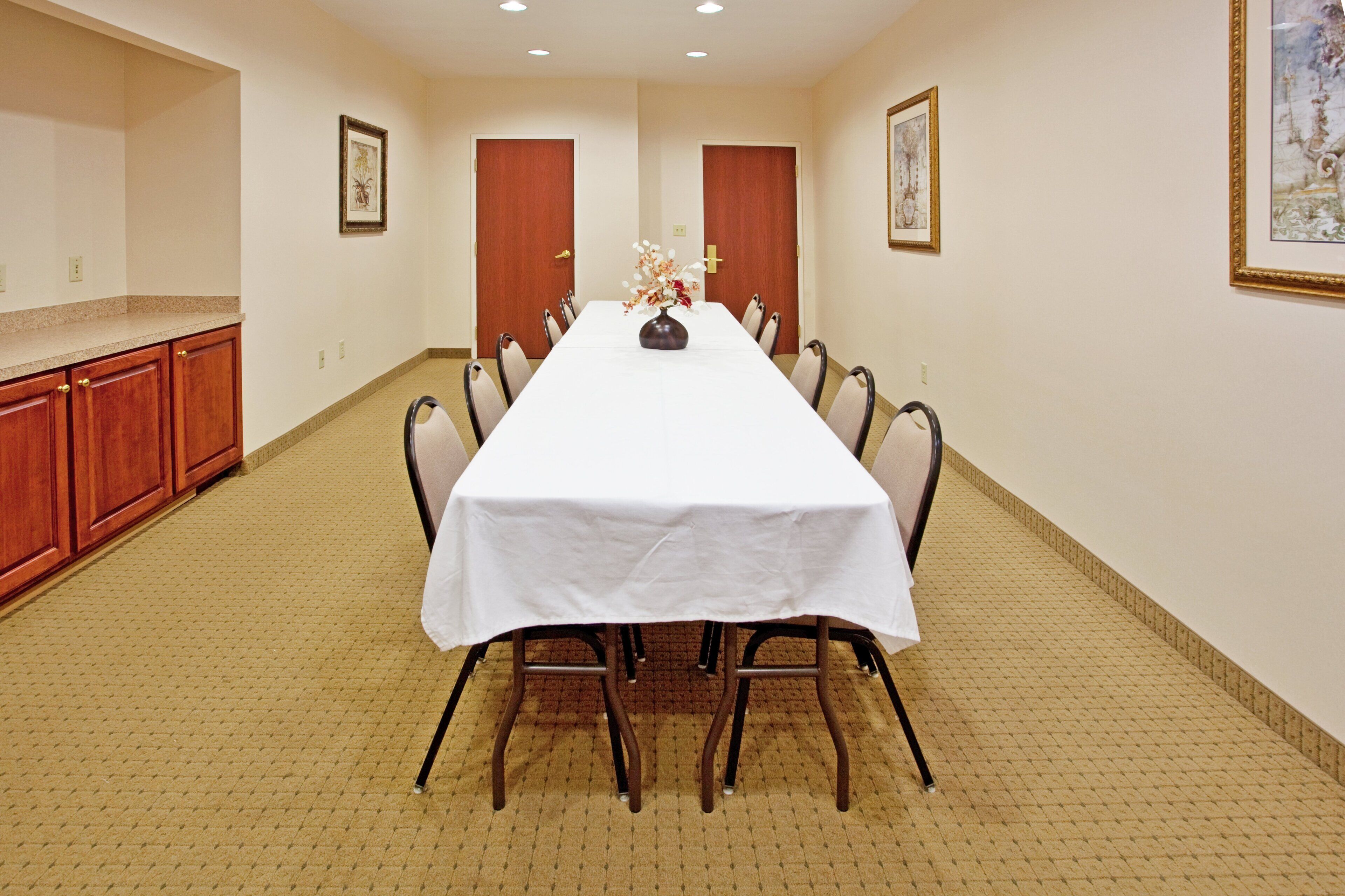 A conference room with a long table, chairs, and a vase of flowers.