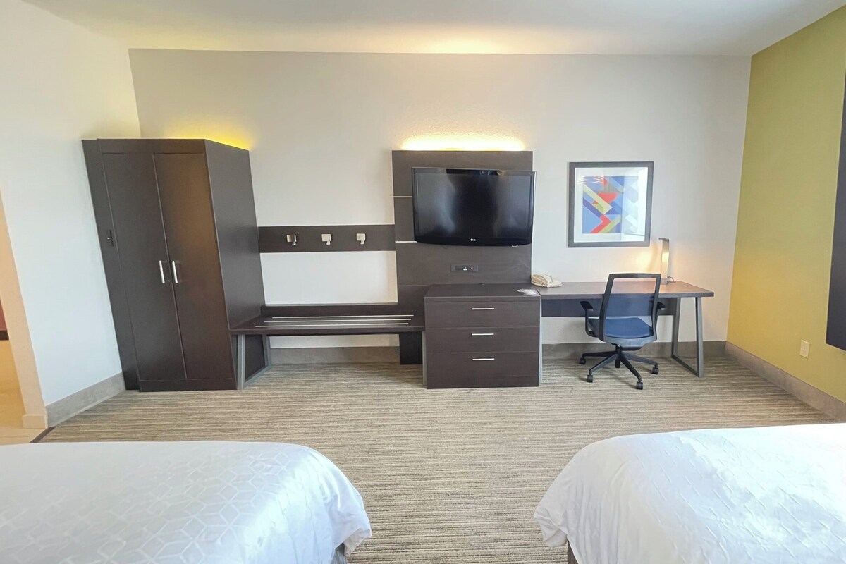 A hotel room with a bed, a desk, a chair, a TV, and a wardrobe.
