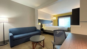 Una habitación de hotel con una cama, un sofá, una mesita y una silla.