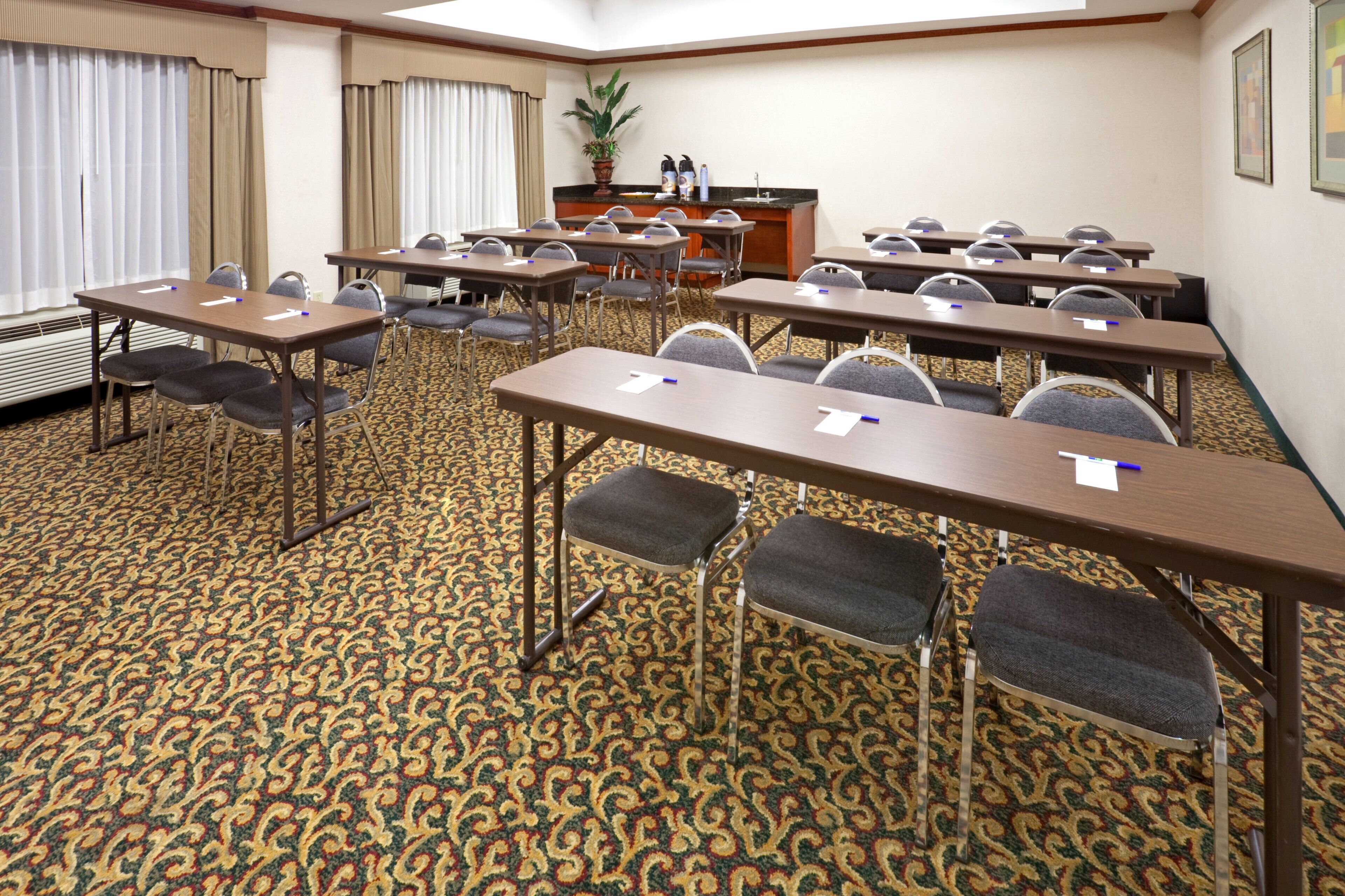 A conference room with multiple tables and chairs, a podium, and a patterned carpet.