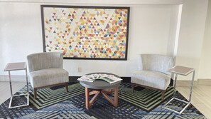A room with two armchairs, a small round table, and a large geometric-patterned wall hanging. - Holiday Inn Express Hotel & Suites Decatur by IHG (Decatur)