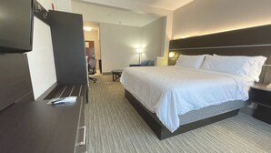 Ett hotellrum med en säng, ett sängbord, en lampa och ett skrivbord med en stol.