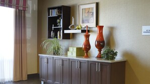 A room with a brown cabinet, a bookshelf, a framed picture, and a sign indicating an ice and vending area.