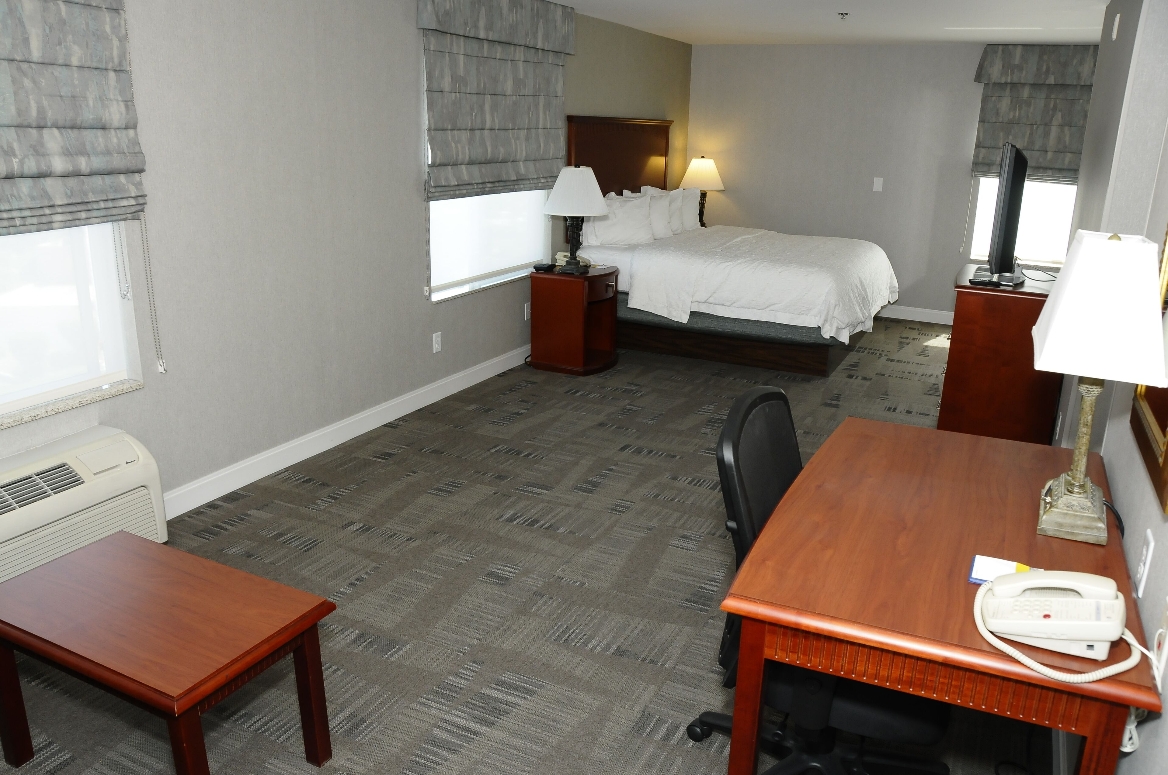 A hotel room with a bed, bedside tables with lamps, a desk with a telephone, and a chair.