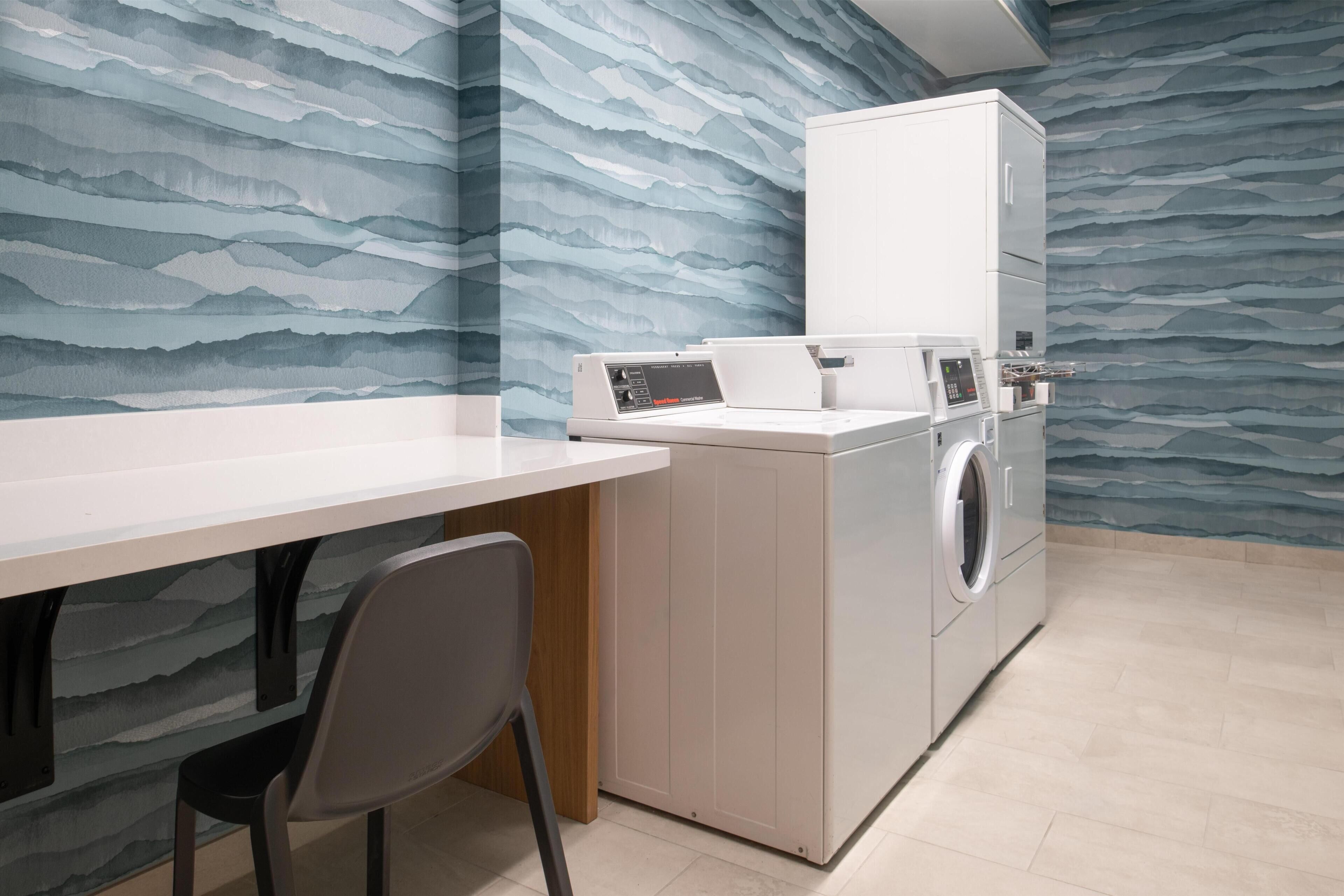 A laundry area with a washing machine, a dryer, and a table with a chair.