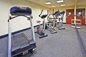 Un gimnasio con cintas de correr, elípticas y una banca.