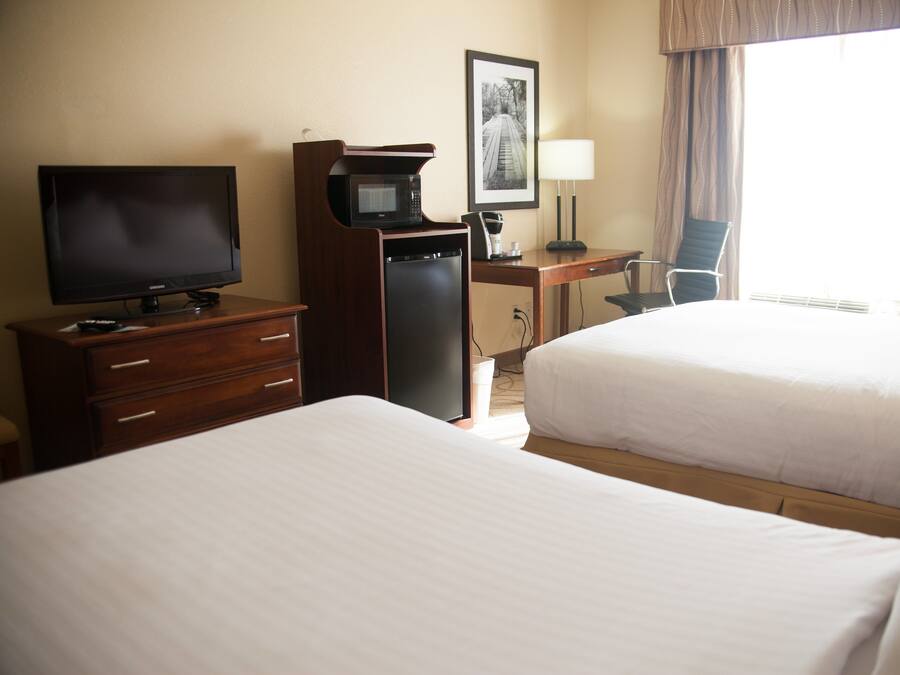 Habitación de hotel con dos camas, un escritorio con lámpara, televisión y microondas.
