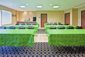 A conference room with multiple tables and chairs, a kitchenette, and a door. - Holiday Inn Express Hotel & Suites Paragould by IHG (Paragould)