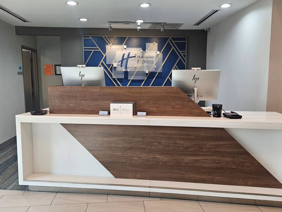 A hotel reception desk with a modern design, a digital display, and a sign indicating 'Holiday Inn Express & Suites'.