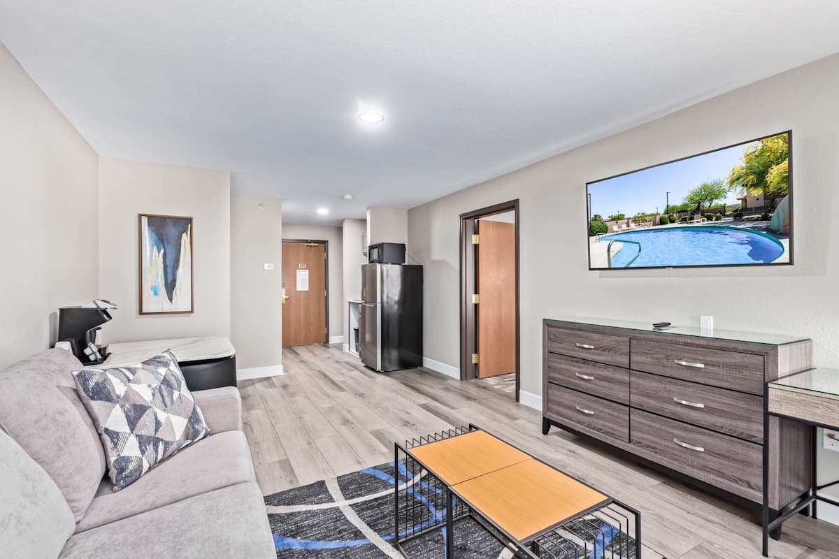 A modern living room with a sofa, coffee table, and a TV mounted on the wall.