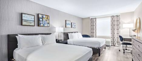 Een hotelkamer met twee bedden, een bureau, een stoel en kunstwerken aan de muren.