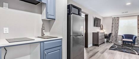 A modern kitchen with blue cabinets, a stainless steel refrigerator, and a white countertop.