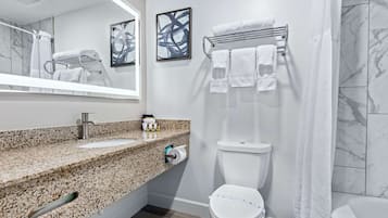 Een moderne badkamer met een granieten aanrechtblad, een toilet, een handdoekhouder en een douchegordijn.
