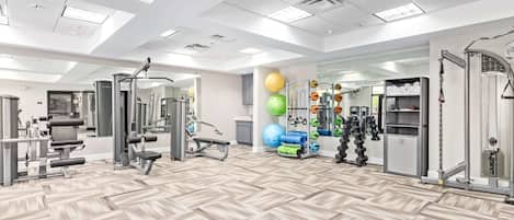 A spacious gym with various exercise equipment, mirrored walls, and a patterned floor.