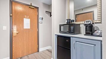 A kitchenette with a microwave, coffee maker, and refrigerator.