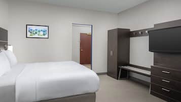 Ein Hotelzimmer mit Bett, Fernseher, Kleiderschrank und einer Tür zu einem weiteren Raum.