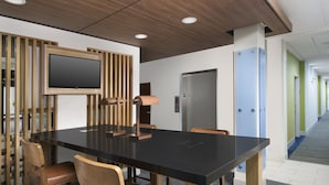 A conference room with a large table, chairs, a television, and a door. - Holiday Inn Express Knoxville-Strawberry Plains by IHG (Knoxville)