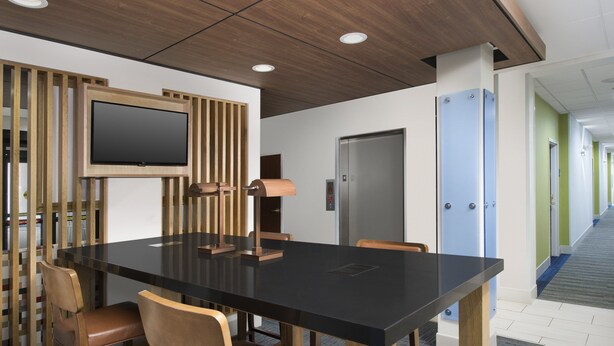 A conference room with a large table, chairs, a television, and a door. - Holiday Inn Express Knoxville-Strawberry Plains by IHG (Knoxville)