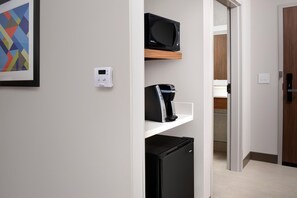Une cuisine moderne équipée d’un four à micro-ondes, d’une machine à café et d’un réfrigérateur, le tout placé sur une étagère blanche.