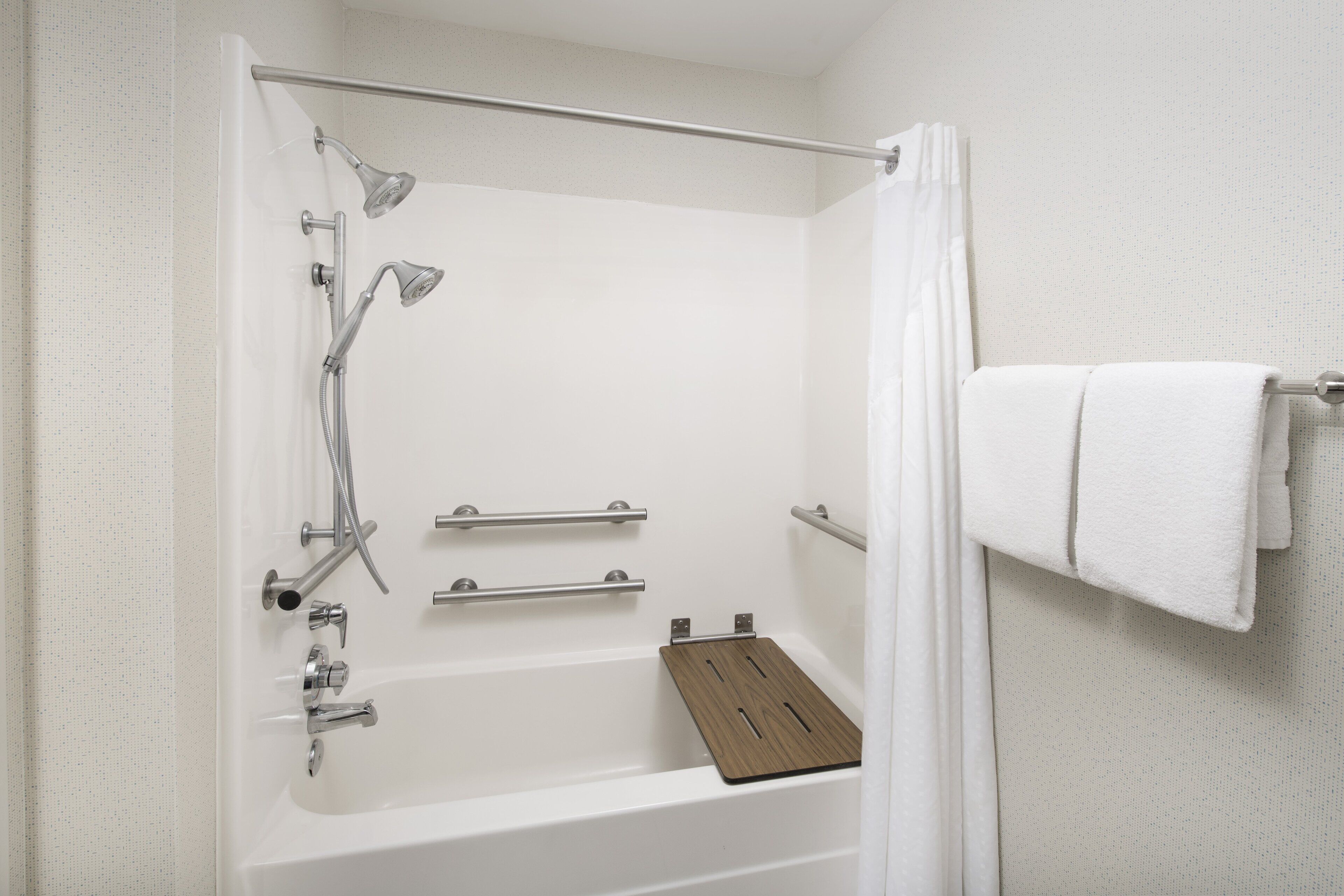 A modern bathroom with a bathtub, shower, and towel rack.