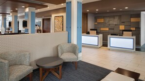 A lobby with a reception desk, seating area, and a patterned wall. - Holiday Inn Express Knoxville-Strawberry Plains by IHG (Knoxville)