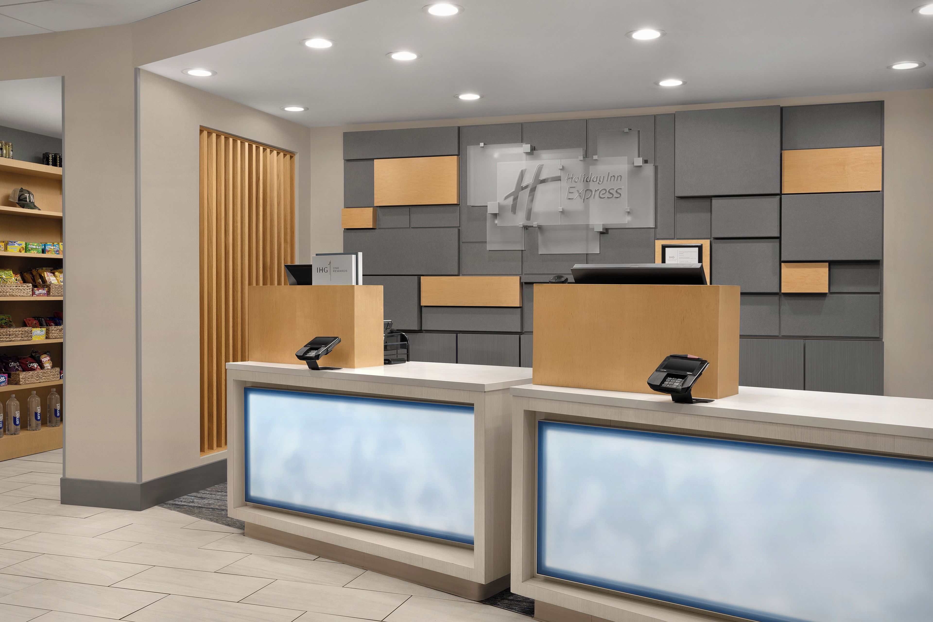 A hotel reception area with two counters, a wooden panel wall, and a shelf with snacks.