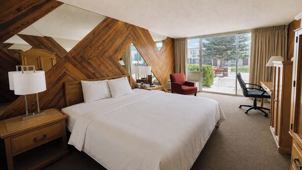 Habitación de hotel con una cama grande, un escritorio, una silla y vistas al exterior.