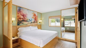 Une chambre avec un lit en bois, un tableau au mur et un grand miroir.