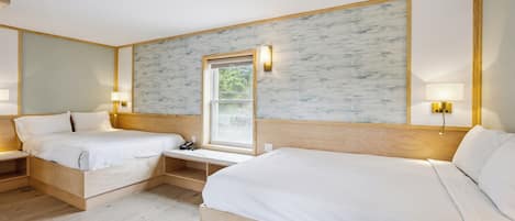 Hotellihuone, jossa on kaksi erillistä sänkyä, puiset päätyosat, ikkuna, josta on näkymä, ja seinään kiinnitetyt lamput.