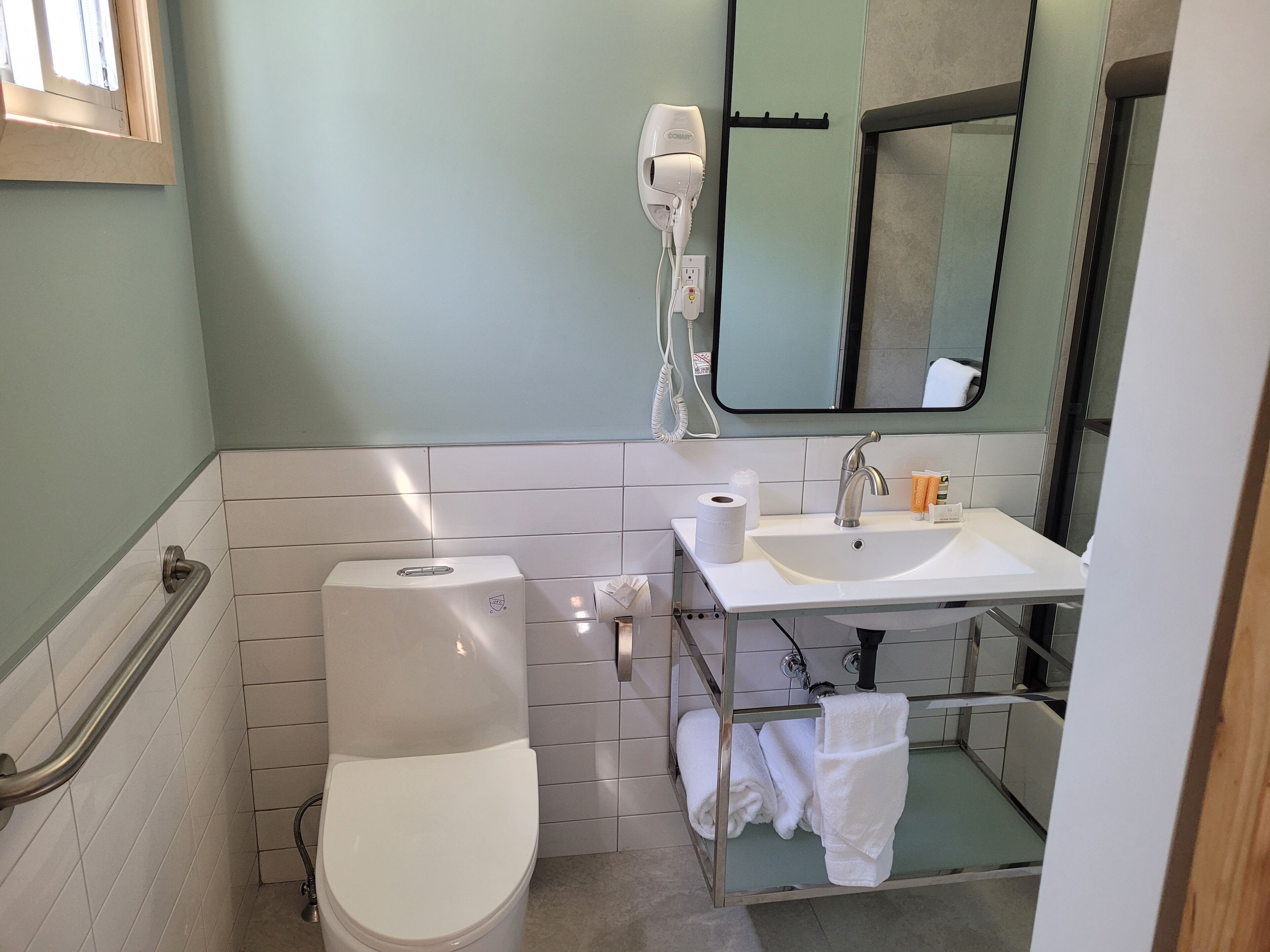 A bathroom with a toilet, sink, and hand dryer.