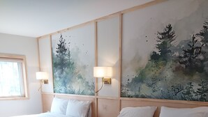 A hotel room with two single beds, wooden headboards, and a large wall mural of trees.
